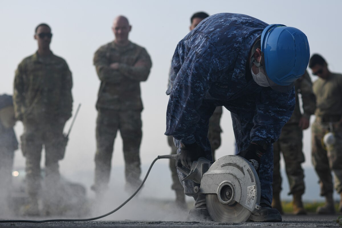 A member of the Japan Maritime Self-Defense Force cuts concrete to perform a spall repair at Kanoya Air Base, Japan, May 15, 2023. A four-man team from Yokota Air Base went to Kanoya to teach Japan Maritime Self-Defense Force engineers how to complete a spall repair. (U.S. Air Force photo by Staff Sgt. Spencer Tobler)