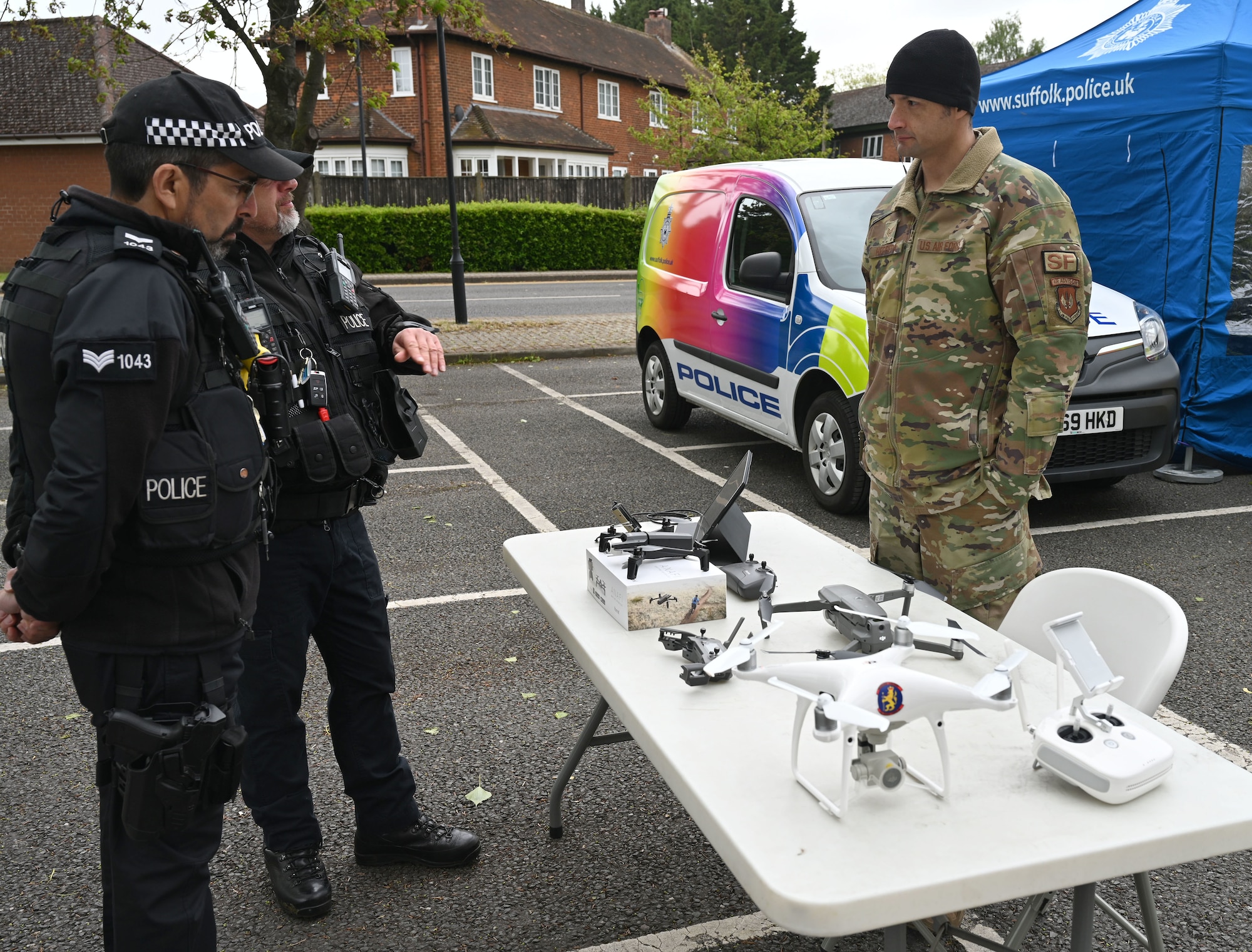 U.S. Air Force Staff Sgt. David Herrera, right, 100th Security Forces Squadron counter - small unmanned aerial system operation (known as C-SUAS) NCO in charge, shares information about using drones for training and testing with Sgt. Chris Louka, left, and Police Constable Bernie Manning, both Ministry of Defence Police authorized firearms/counterterrorism officers, during at the Police Week show-and-tell event at Royal Air Force Mildenhall, England, May 15, 2023. This year’s events include a ruck march, Defenders’ Challenge, “jail and bail,” and Fallen Defender memorial. (U.S. Air Force photo by Karen Abeyasekere)