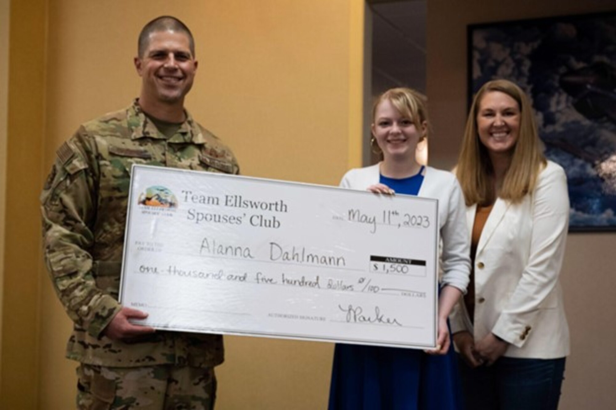 U.S. Air Force Col. Seth Spanier, 28th Bomb Wing vice commander (left), and Leah Parker, Team Ellsworth Spouse Club scholarship chair (right), present a scholarship check to Alanna Dahlman, scholarship recipient (center) at Ellsworth Air Force Base, S.D., May 11, 2023. The scholarship is presented once a year to qualifying spouses with Ellsworth AFB. (U.S. Air Force photo by Airman 1st Class Josephine Pepin)