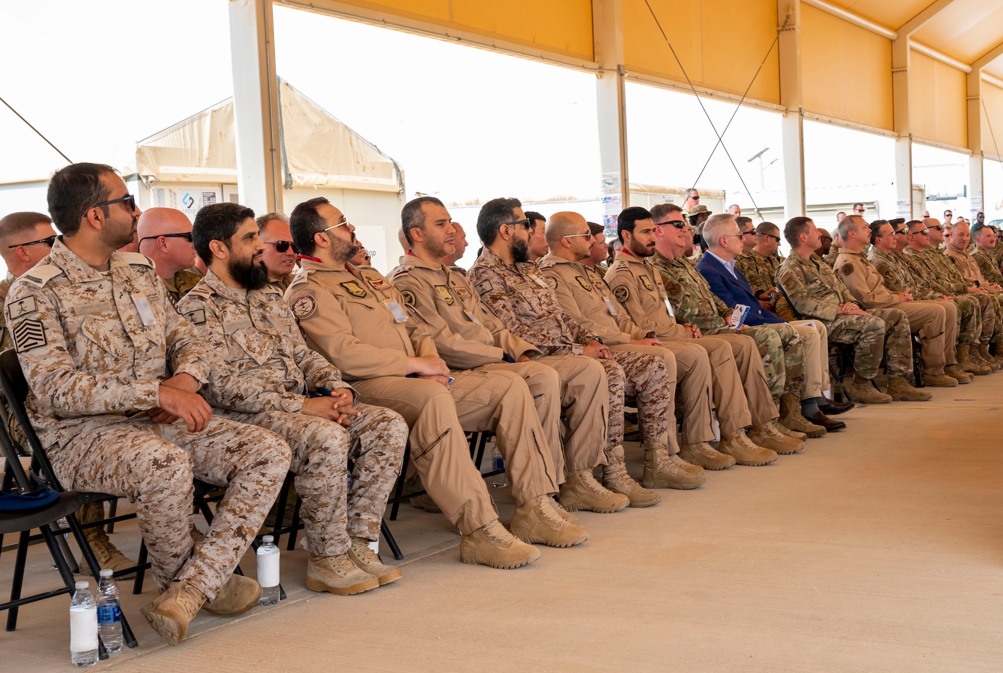 Leadership from the Royal Saudi Air Force and 378th Air Expeditionary Wing listen to a speech during a change of command ceremony at Prince Sultan Air Base, Kingdom of Saudi Arabia, May 18, 2023. During the ceremony, Brig. Gen. William Betts relinquished command of the 378th AEW to Brig. Gen. Akshai Gandhi. The tradition of change of command ceremonies are to allow service members to witness their new leader assume the responsibility and trust associated with the position of commander. (U.S. Air Force photo by Senior Airman Stephani Barge)