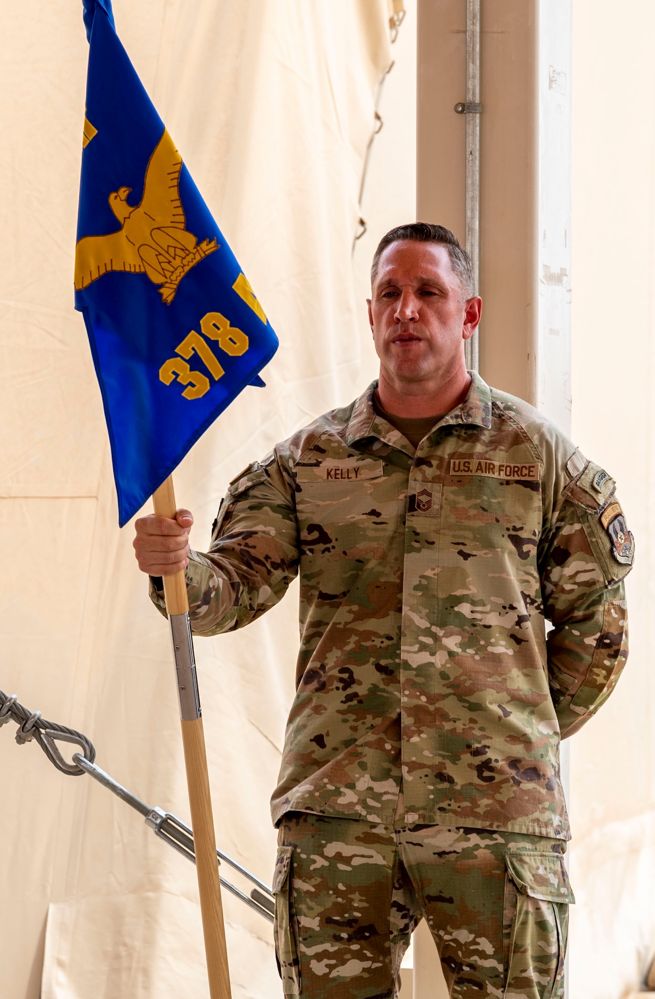 U.S. Air Force Chief Master Sgt. William Kelly, 378th Air Expeditionary Wing command chief, holds the guidon during a change of command ceremony at Prince Sultan Air Base, Kingdom of Saudi Arabia, May 18, 2023. During the ceremony, Brig. Gen. William Betts relinquished command of the 378th AEW to Brig. Gen. Akshai Gandhi. The tradition of change of command ceremonies are to allow service members to witness their new leader assume the responsibility and trust associated with the position of commander. (U.S. Air Force photo by Senior Airman Stephani Barge)