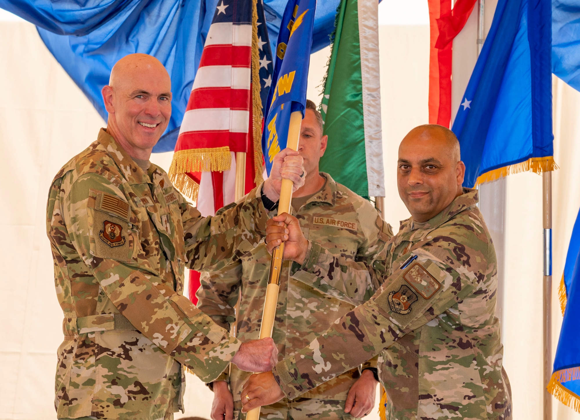 U.S. Air Force Brig. Gen. Akshai Gandhi, right, incoming commander of the 378th Air Expeditionary Wing, assumes command from Maj. Gen. Clark Quinn, left, Ninth Air Force deputy commander, during a change of command ceremony at Prince Sultan Air Base, Kingdom of Saudi Arabia, May 18, 2023. During the ceremony, Brig. Gen. William Betts relinquished command of the 378th AEW to Gandhi. The tradition of change of command ceremonies are to allow service members to witness their new leader assume the responsibility and trust associated with the position of commander. (U.S. Air Force photo by Senior Airman Stephani Barge)