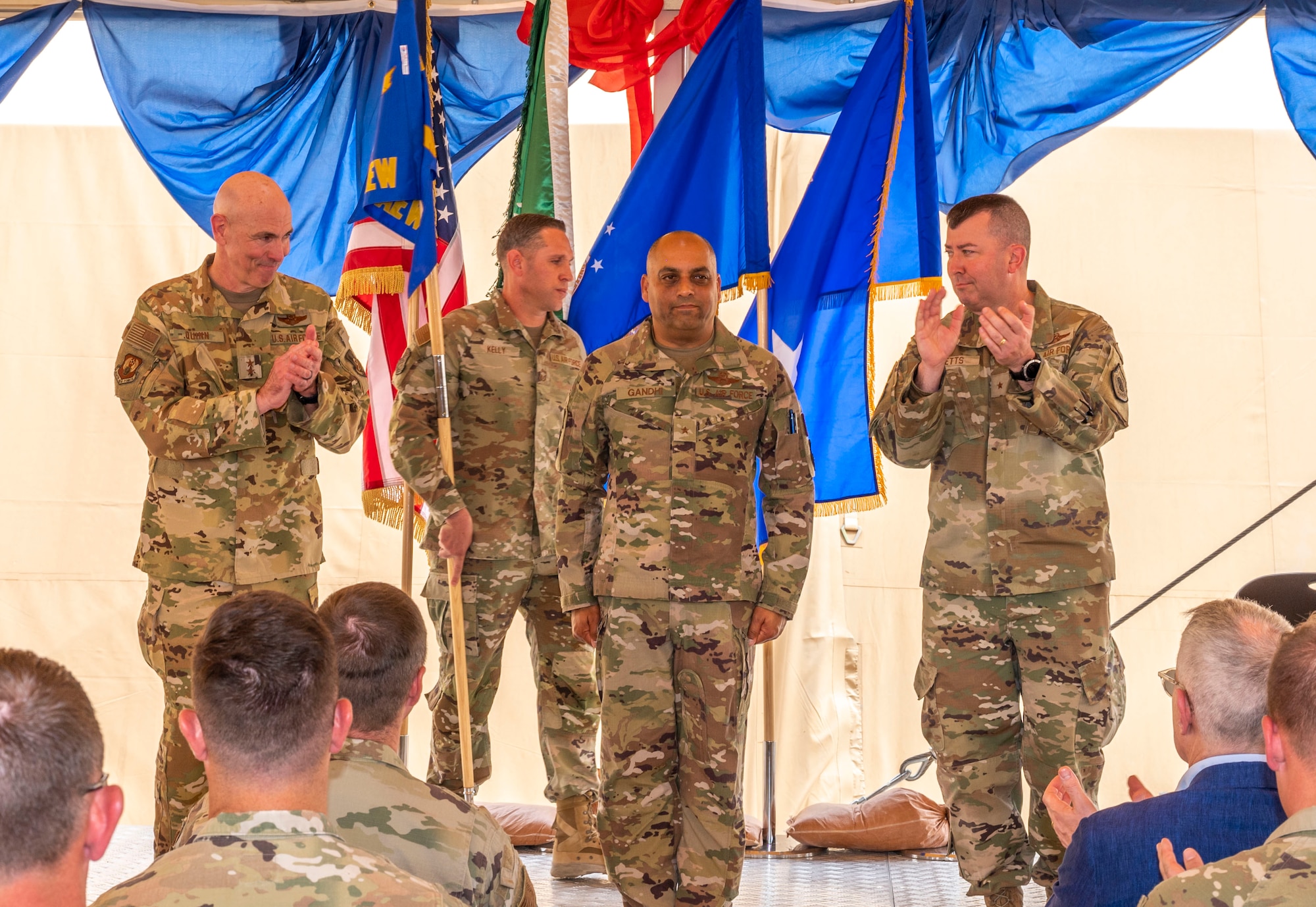 U.S. Air Force Brig. Gen. Akshai Gandhi, center, is applauded after assuming command of the 378th Air Expeditionary Wing from Maj. Gen. Clark Quinn, left, Ninth Air Force deputy commander, during a change of command ceremony at Prince Sultan Air Base, Kingdom of Saudi Arabia, May 18, 2023. During the ceremony, Brig. Gen. William Betts relinquished command of the 378th AEW to Gandhi. The tradition of change of command ceremonies are to allow service members to witness their new leader assume the responsibility and trust associated with the position of commander. (U.S. Air Force photo by Senior Airman Stephani Barge)