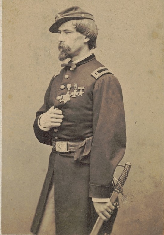 A man in uniform holds a scabbard.