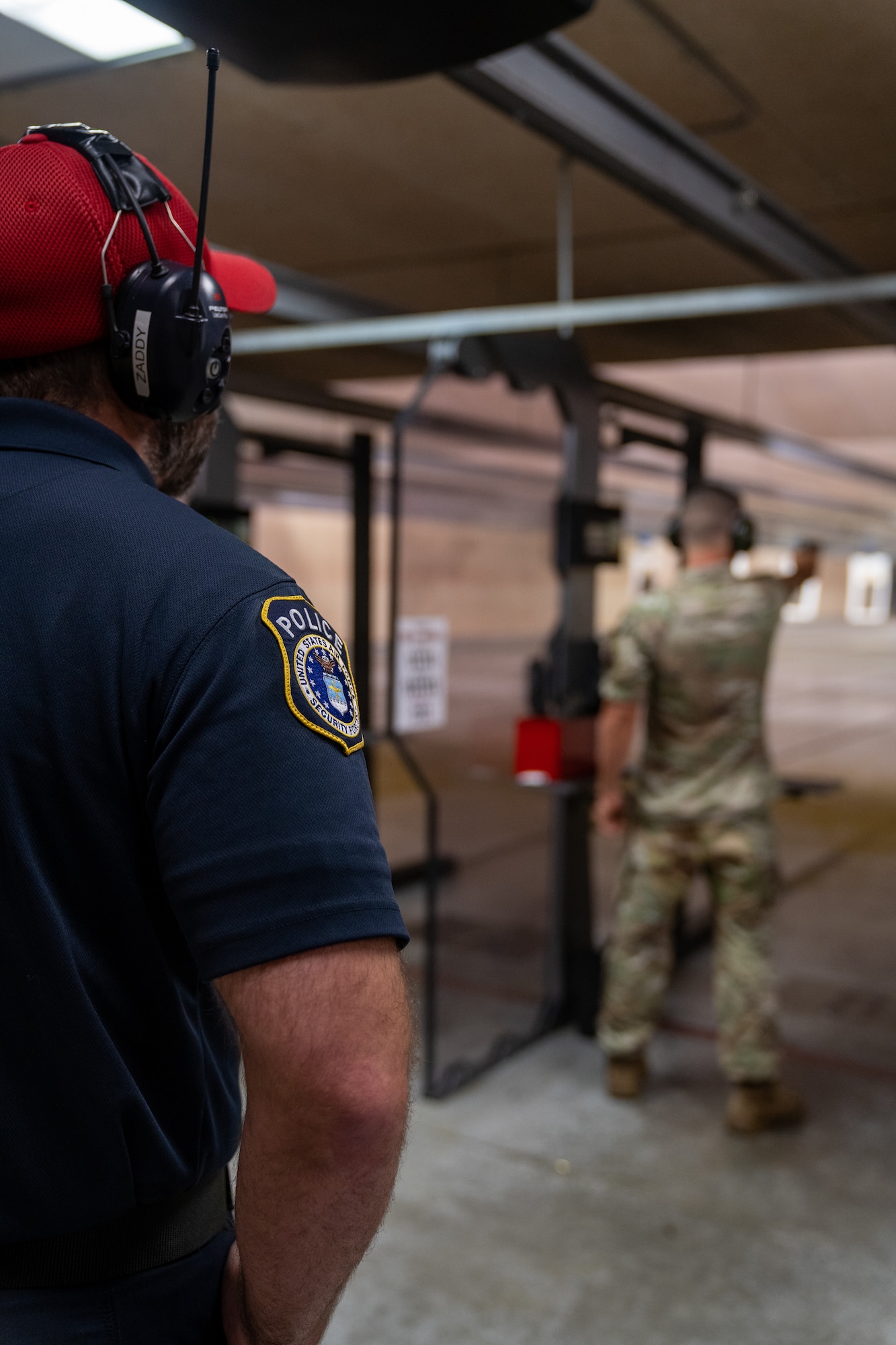 Officer Zach Kaletsch, 81st Security Forces Squadron combat arms instructor, monitors the firing line while U.S. Air Force Staff Sgt. Jesse Wynn, 81st SFS combat arms training and maintenance, fires one handed at his target during the National Police Week pistol competition at Keesler Air Force Base, Mississippi, May 17, 2023.