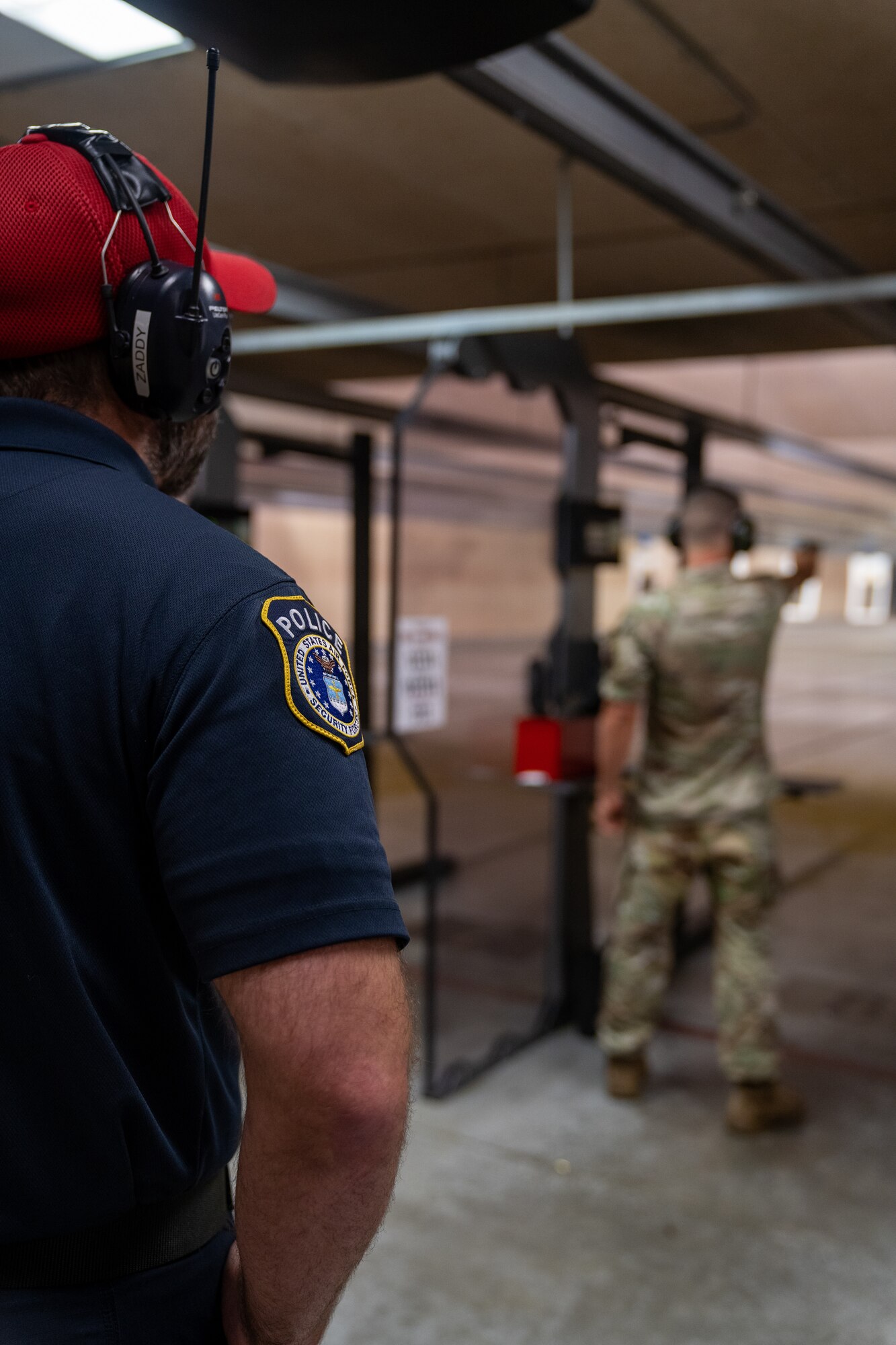 Officer Zach Kaletsch, 81st Security Forces Squadron combat arms instructor, monitors the firing line while U.S. Air Force Staff Sgt. Jesse Wynn, 81st SFS combat arms training and maintenance, fires one handed at his target during the National Police Week pistol competition at Keesler Air Force Base, Mississippi, May 17, 2023.