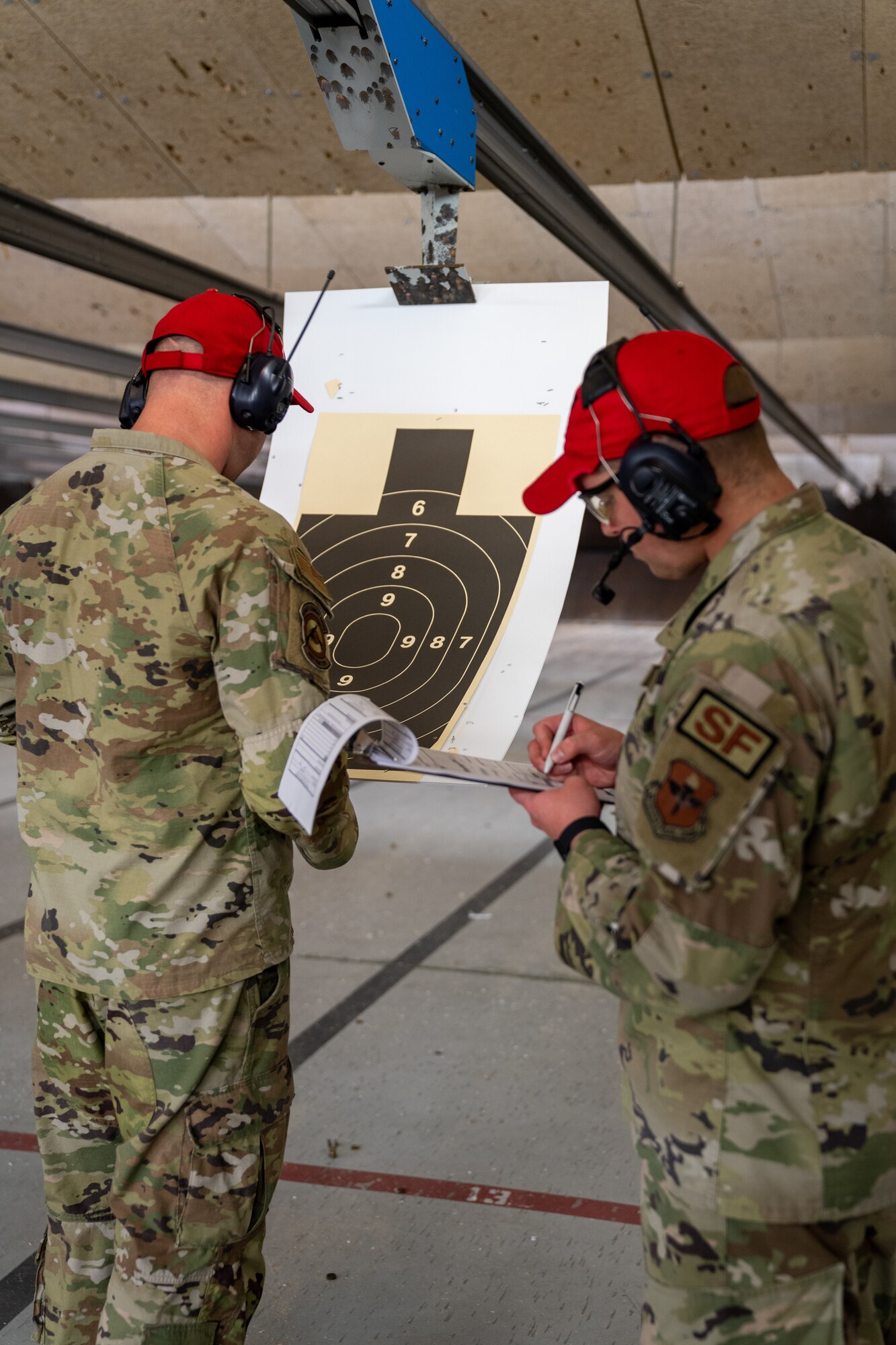 U.S. Staff Sgt. David Evens and Senior Airman Dean Webb, 81st Security Forces Squadron combat arms instructors, score a target during the National Police Week Pistol Competition at Keesler Air Force Base, Mississippi, May 17, 2023.