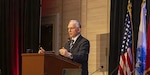 Crop of nps.edu photo Hon. Guertin giving a speech  the 20th NPS Acquistion Research Symposium