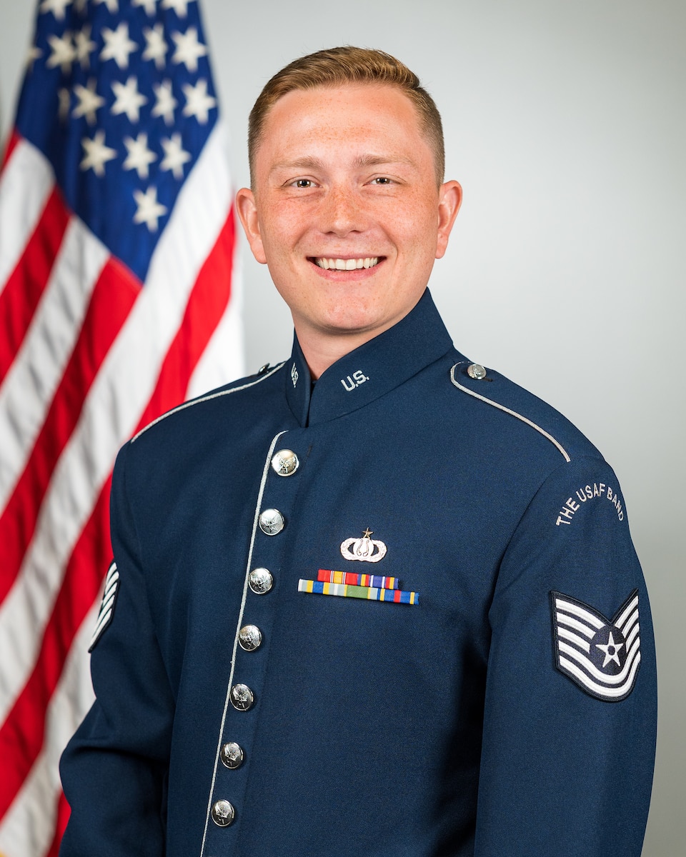 Official photo of A1C Benton Felty, vocalist with Full Spectrum and  Concert Band, two of six ensembles in the Air Force Heritage of America Band, Langley AFB, VA.  A1C Felty is wearing blue service dress in front of an American flag.
