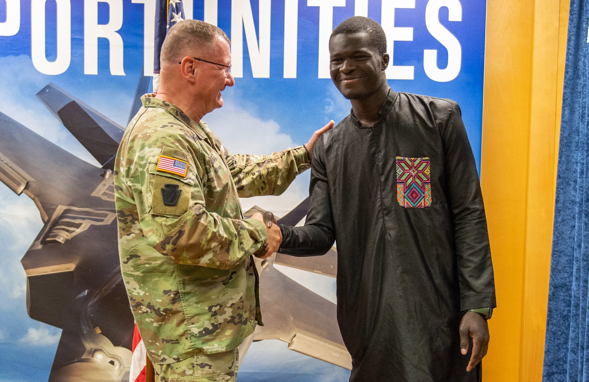 The newest member of the 158th Fighter Wing, Airman Libass Mbengue, shakes hands with Maj. Gen. Gregory Knight, adjutant general of the Vermont National Guard, at Vermont Air National Guard Base, South Burlington, Vermont, May 18, 2023. Mbengue moved to Vermont in 2018 from Senegal, Africa.