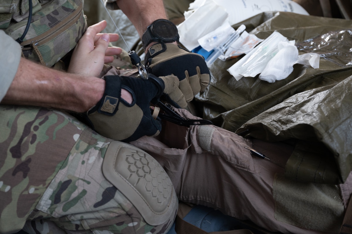 U.S. Air Force Staff Sgt. Cord Meyer, 48th Rescue Squadron pararescueman, cuts the uniform of 1st Lt. Thomas Colvin, a simulated downed-pilot, over Arizona, May 13, 2023. Service members are taught Tactical Combat Casualty Care in order to provide lifesaving care to injured combatants while preventing additional casualties. (U.S. Air Force photo by Airman 1st Class Jasmyne Bridgers-Matos)