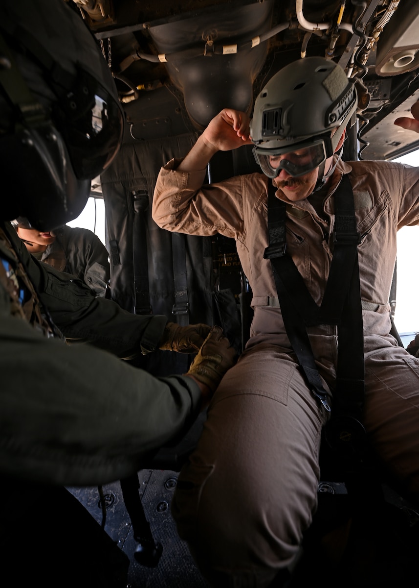 U.S. Marine Corps Master Sgt. Zachary Franks, Marine Light Attack Helicopter Squadron 775 crew chief instructor, buckles in U.S. Air Force 1st Lt. Jessy Sawyer, 12th Airborne Command and Control Squadron air battle manager and simulated downed aviator, during the RED FLAG-Rescue 23-1 training exercise over various places in Arizona, May 13, 2023. The HMLA 775 showcased their tactical recovery of aircraft and personnel (TRAP) skills to the joint service members and learned U.S. Air Force combat search and rescue techniques. (U.S. Air Force photo by Staff Sgt. Abbey Rieves)
