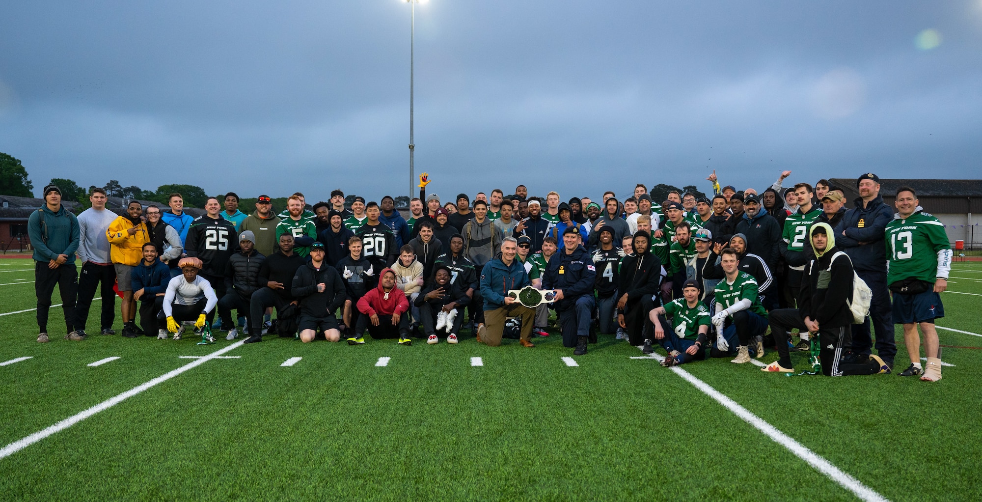 Group photo of U.S. Air Force and U.K. Armed Forces members posing for a photo after a flag football game at Royal Air Force Lakenheath