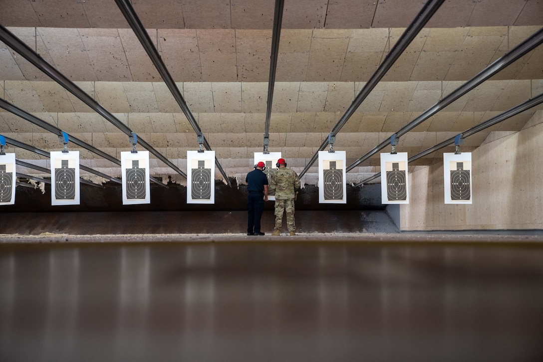 Two instructors review target practice results at a gun range.