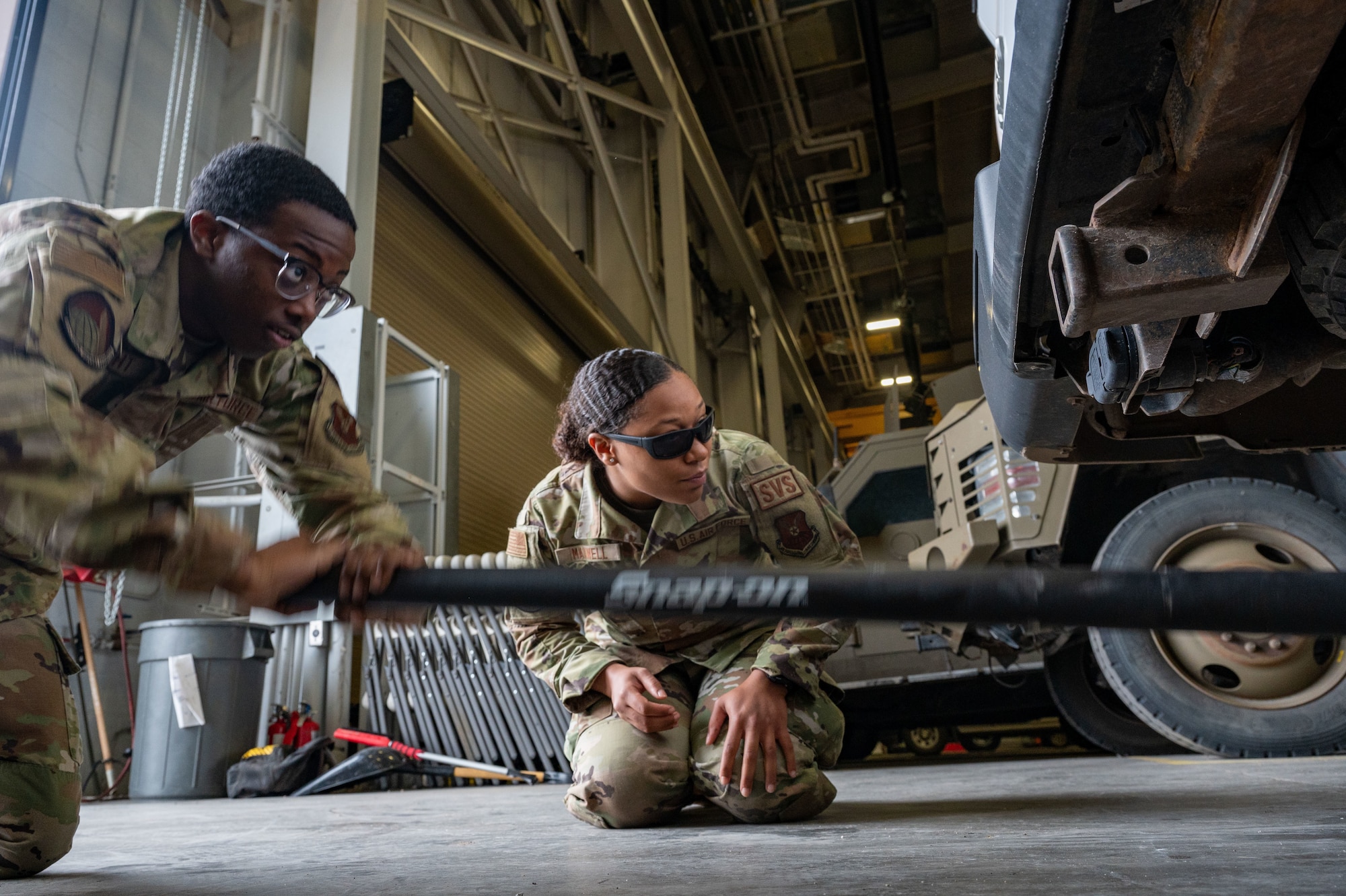 two airman lifting a vehicle with a jack