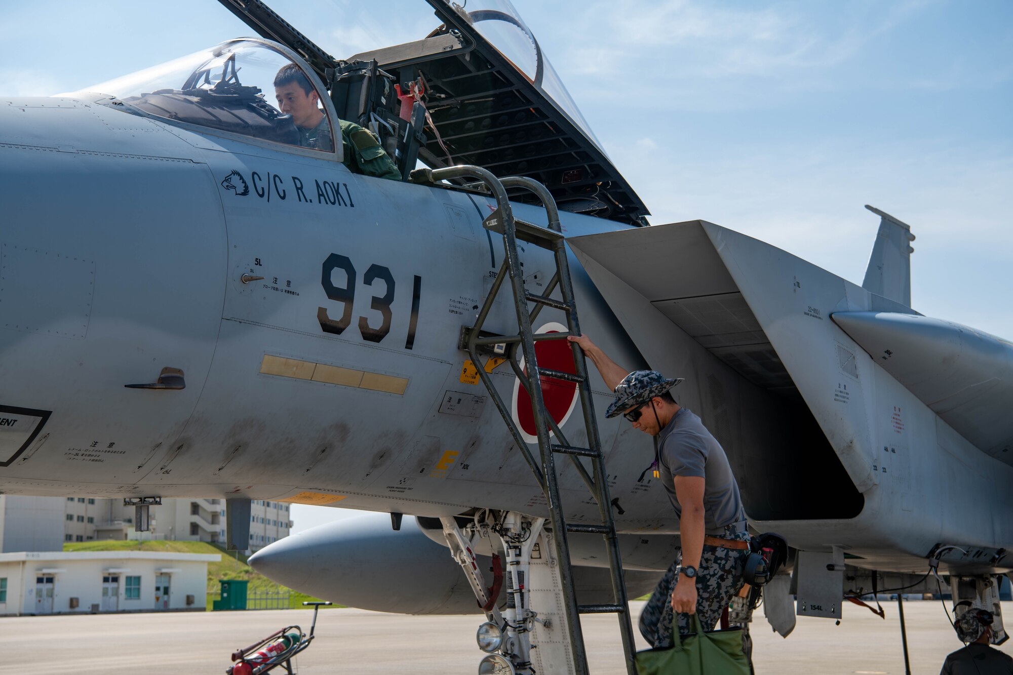 A Japanese Maintenance technician helps a Japanese Pilot before take off for a practice exercise