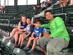 Mother, two children and father sit in stadium seats