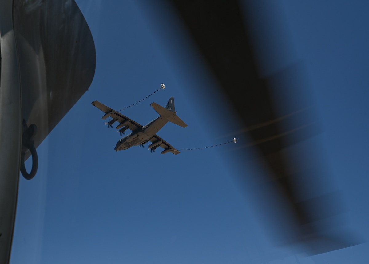 An aircraft flies above a helicopter.