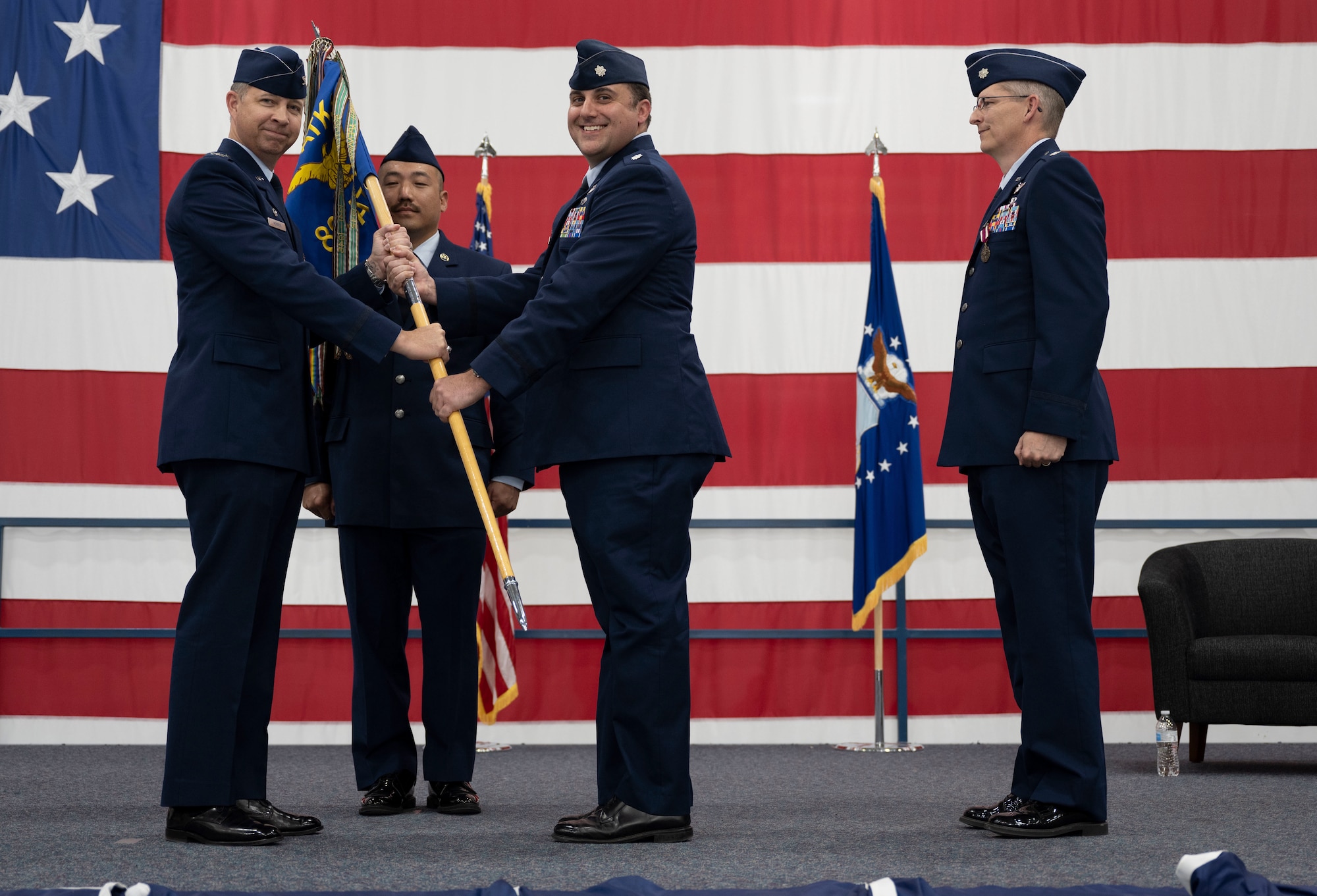 U.S. Air Force Col. Timothy Monroe, 25th Attack Group commander, presents the 89th Attack Squadrons guidon to Lt. Col. Eric Bliss, incoming 89th ATKS commander, at Ellsworth Air Force Base, South Dakota, May 18, 2023.