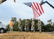 Civilian and military members stand with shovels underneath a U.S. flag.