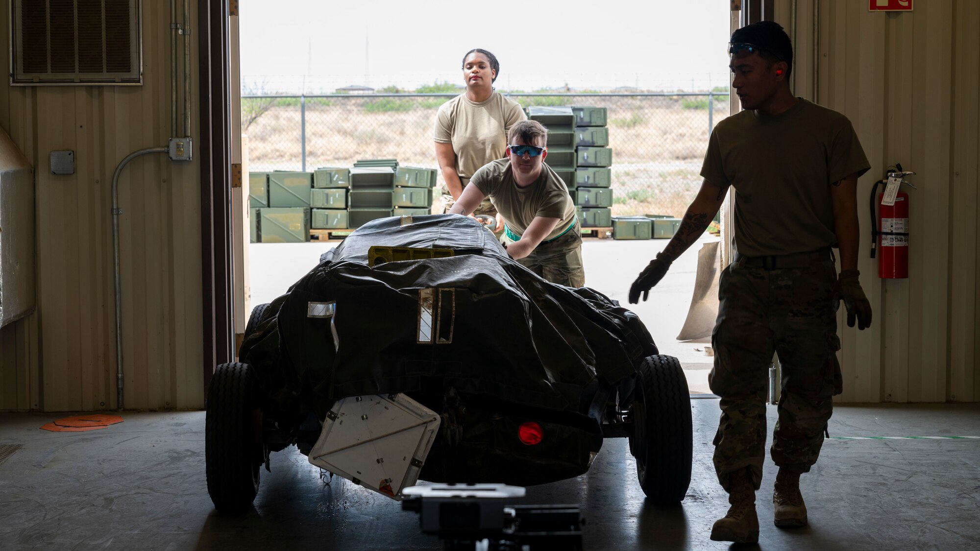 U.S. Air Force Senior Airman Jamiliyah Lindsay, 49th Equipment Maintenance Squadron conventional maintenance crew member, left, moves a belt feeder into a bay with U.S. Air Force Senior Airman Chad Erwin, 49th EMS conventional crew member, center, and U.S. Air Force Staff Sgt. Jonathan Castaneda, 49th EMS munitions crew chief, at Holloman Air Force Base, New Mexico, May 18, 2023.