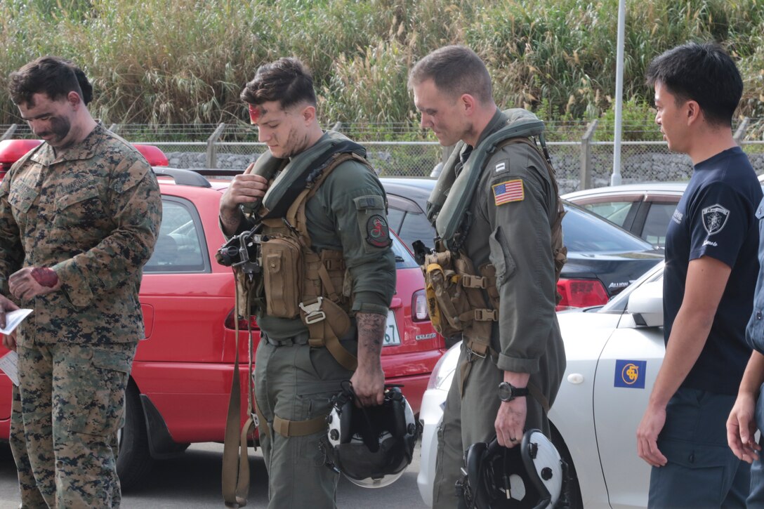 Marines and Japanese base employees who play the role of simulated injured stand by before an air mishap exercise.