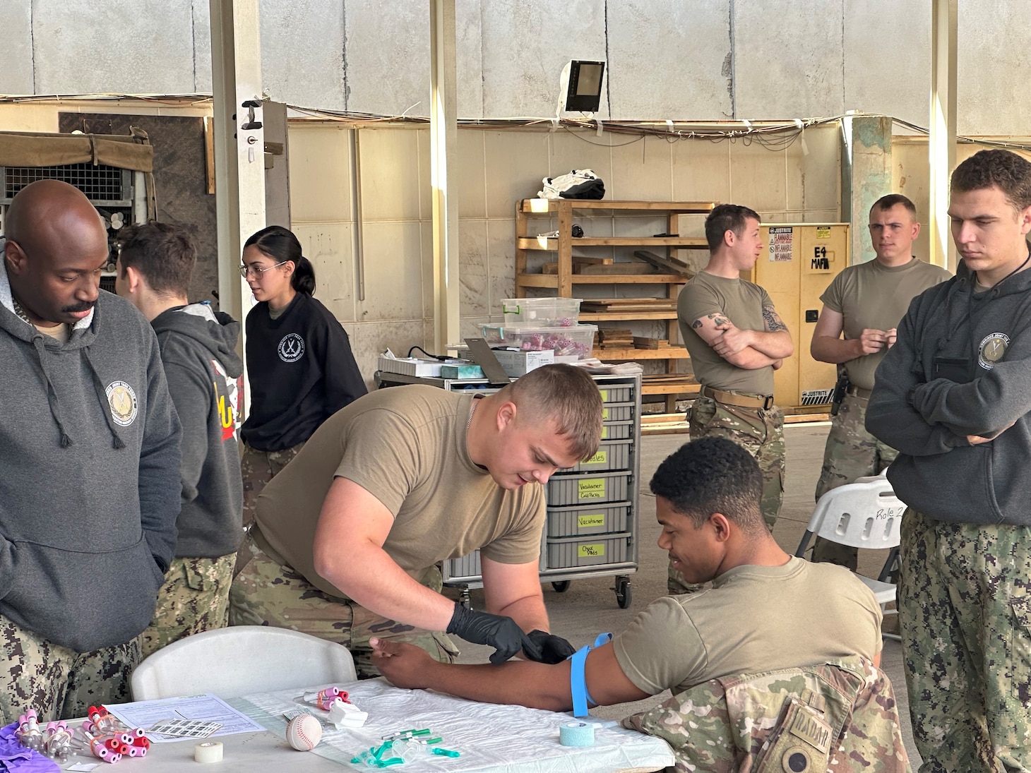 221220-N-N1526-0001 Erbil Air Base, Iraq (Dec. 20, 2023) - Hospital Corpsman 2nd Class Freeman Morrison, a biomedical technician, left, and Lt. j. g. Andrew Mappus, an emergency room nurse, right, assigned to Navy Expeditionary Medical Unit 10- Gulf (NEMU 10G), Rotation 13, are monitoring an U.S. Army Medic Task Force Buckeye, 37th Infantry Brigade Combat Team, as he draws blood from an Army Soldier during the Walking Blood Bank screening rodeo, Dec. 20, 2022.