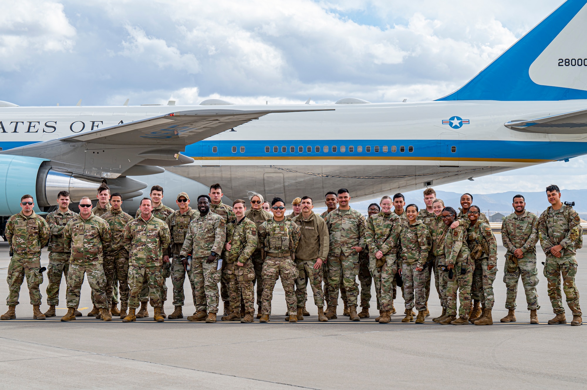 Airmen stand in front of an aircraft.