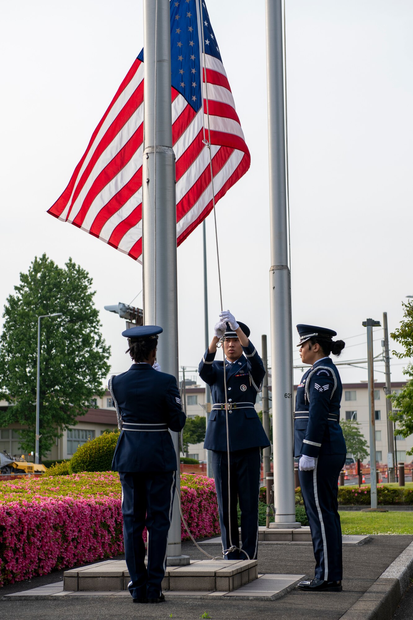 three formal dressed guards lower a flag