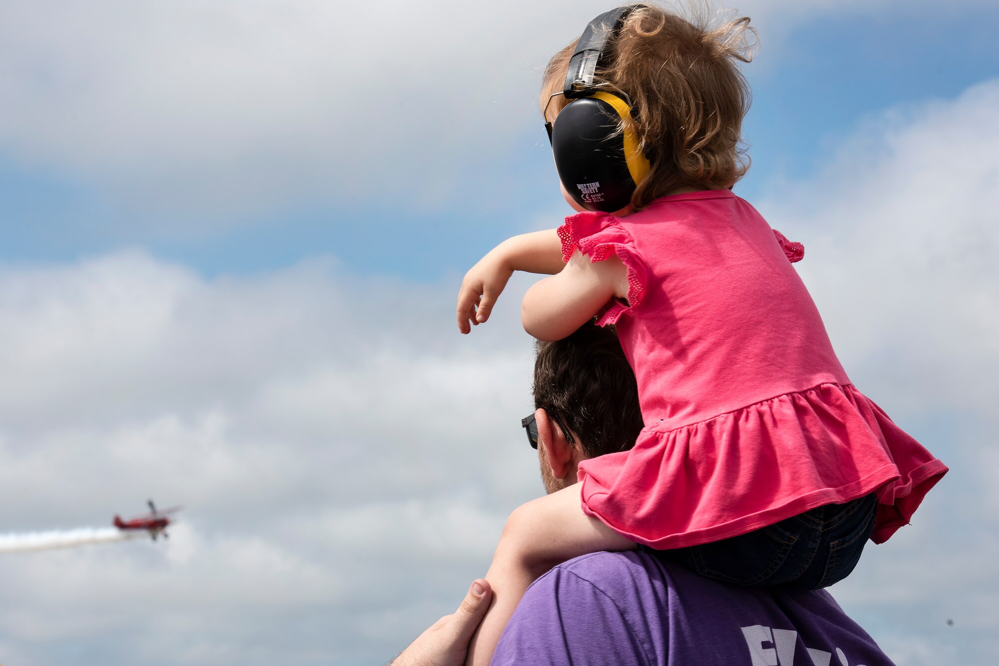 A child watches the Third Strike Wingwalking act during the Wings over Wayne Air Show and Science and Technology Expo at Seymour Johnson Air Force Base, North Carolina, May 20, 2023. Wings over Wayne is a two-day event open to the community that features a variety of aerial demonstrations, ground performances, aircraft static displays, and other events. The event is biennial, and has grown to be the largest free air show in North Carolina. (U.S. Air Force photo by Tech. Sgt. Christopher Hubenthal)