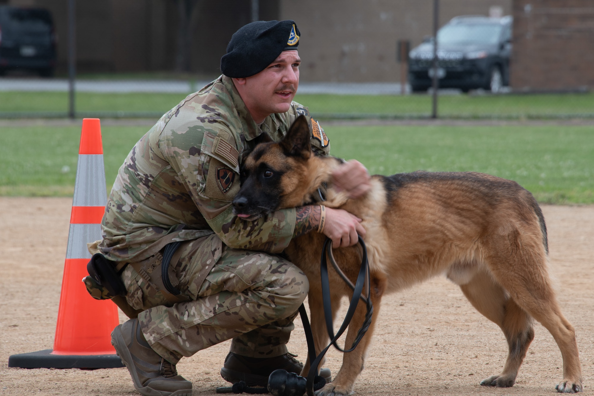 A man in uniform hugs a dog.