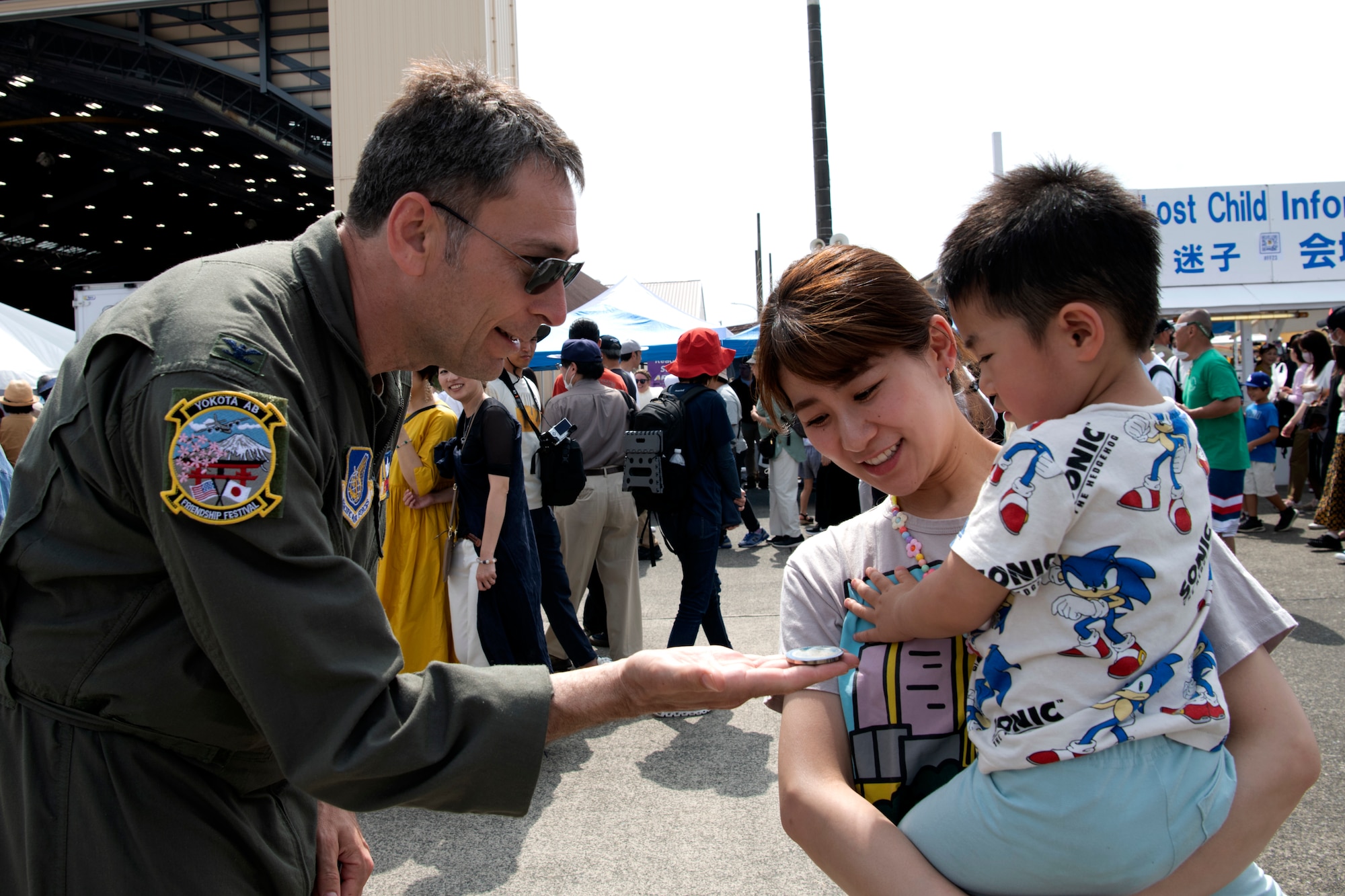 An older pilot gives a patch to a young child held up by their mother