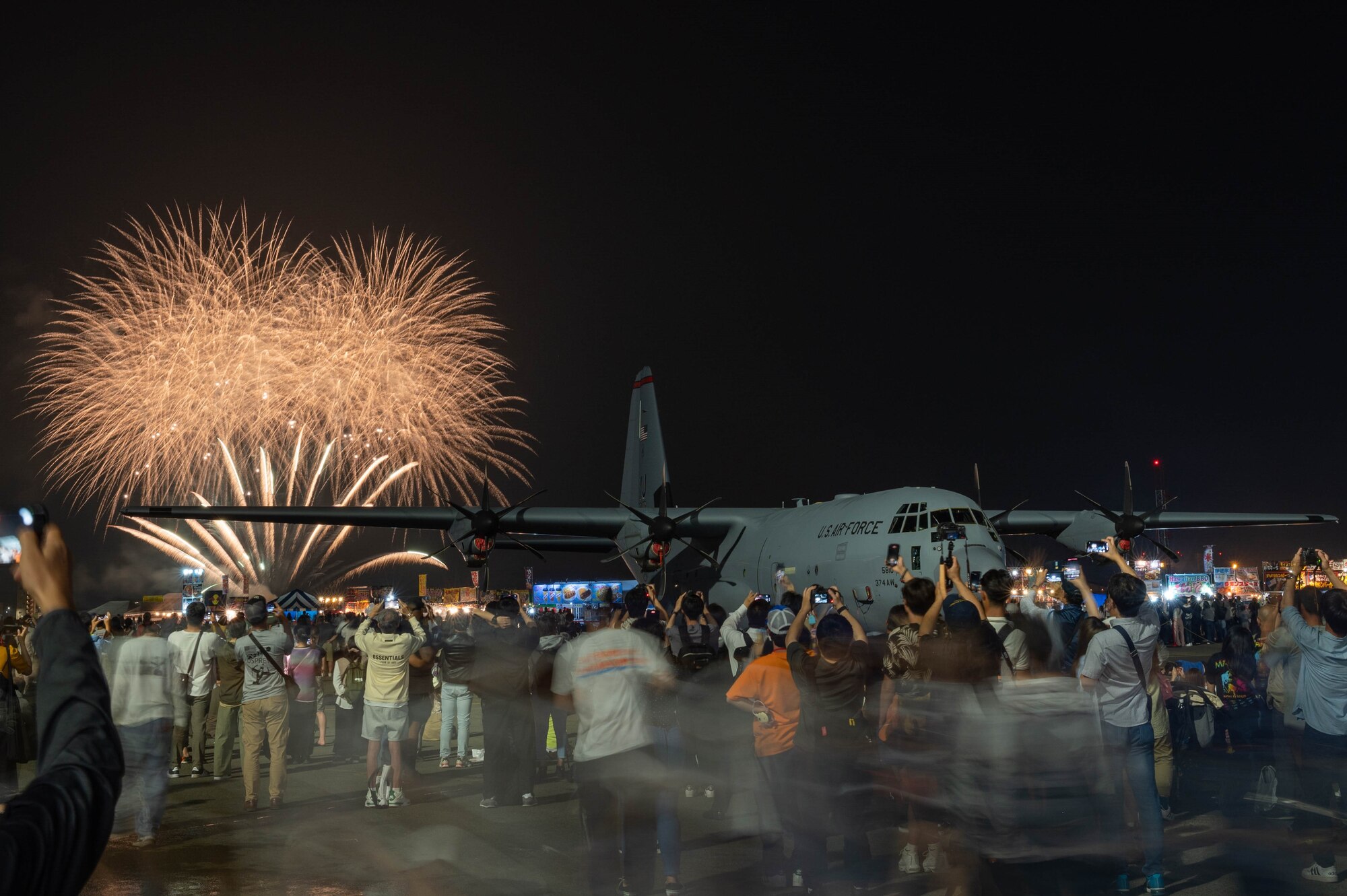 People crowd to watch a fireworks display in front of a C-130 aircraft