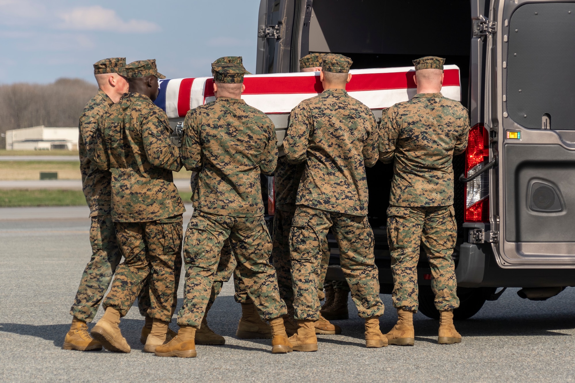 A group of men carry a transfer case.