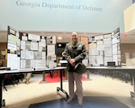 Lt. Col. Alejandro Pascual IV stands before a display he built to honor the World War II service of his great grandfather , Tech. Sgt. Isabelo Viernes, who served with the 45th Infantry Regiment and survived the Bataan Death March.