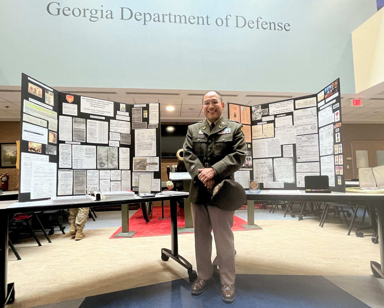 Lt. Col. Alejandro Pascual IV stands before a display he built to honor the World War II service of his great grandfather , Tech. Sgt. Isabelo Viernes, who served with the 45th Infantry Regiment and survived the Bataan Death March.