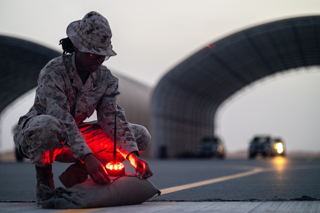 A Marine sets up a red light on a road.