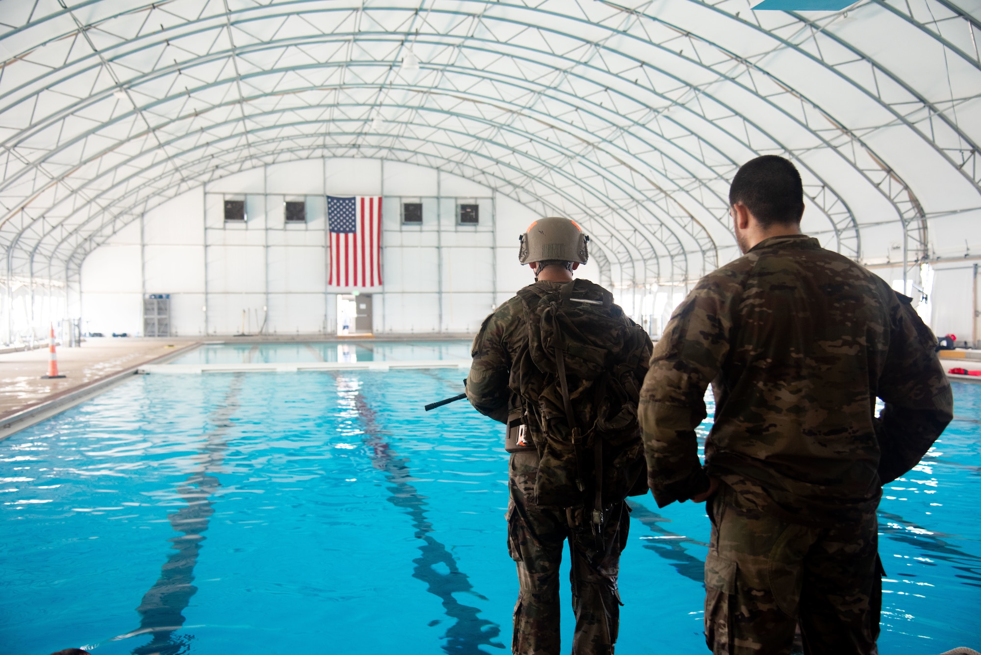 Airmen in full tactical gear stand next to pool