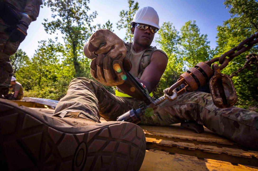 A guardsman uses a tool to screw in a piece of equipment.