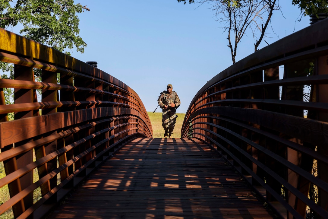 An airman in uniform crosses a bridge alone.