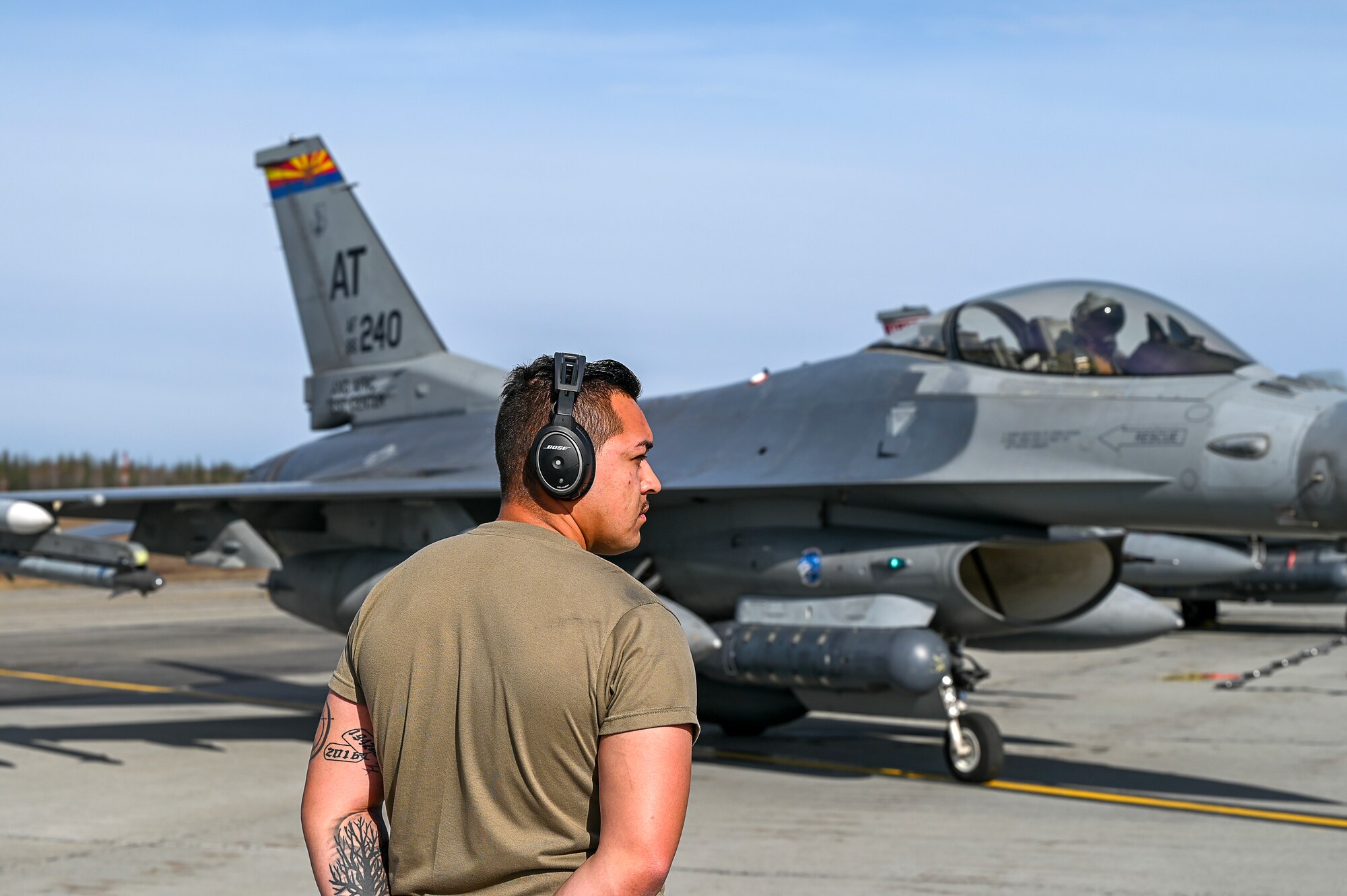 A crew chief assigned to the Air National Guard Air Force Reserve Command Test Center in Tucson, Arizona, prepares to marshal the launch of an F-16 Fighting Falcon at Eielson Air Force Base, Alaska, May 11, 2023, during Northern Edge 2023. The exercise enabled AATC personnel to an electronic warfare countermeasure that can be housed in removable, adaptable pods under aircraft wings or fuselages.