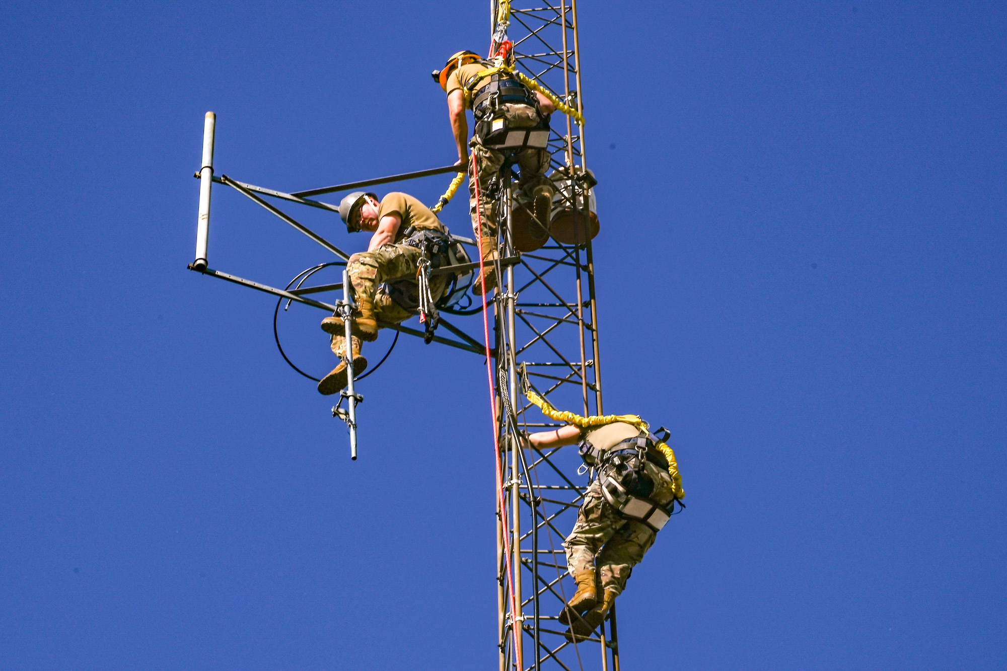 People wearing hard hats and harnesses prepare to climb a structure.