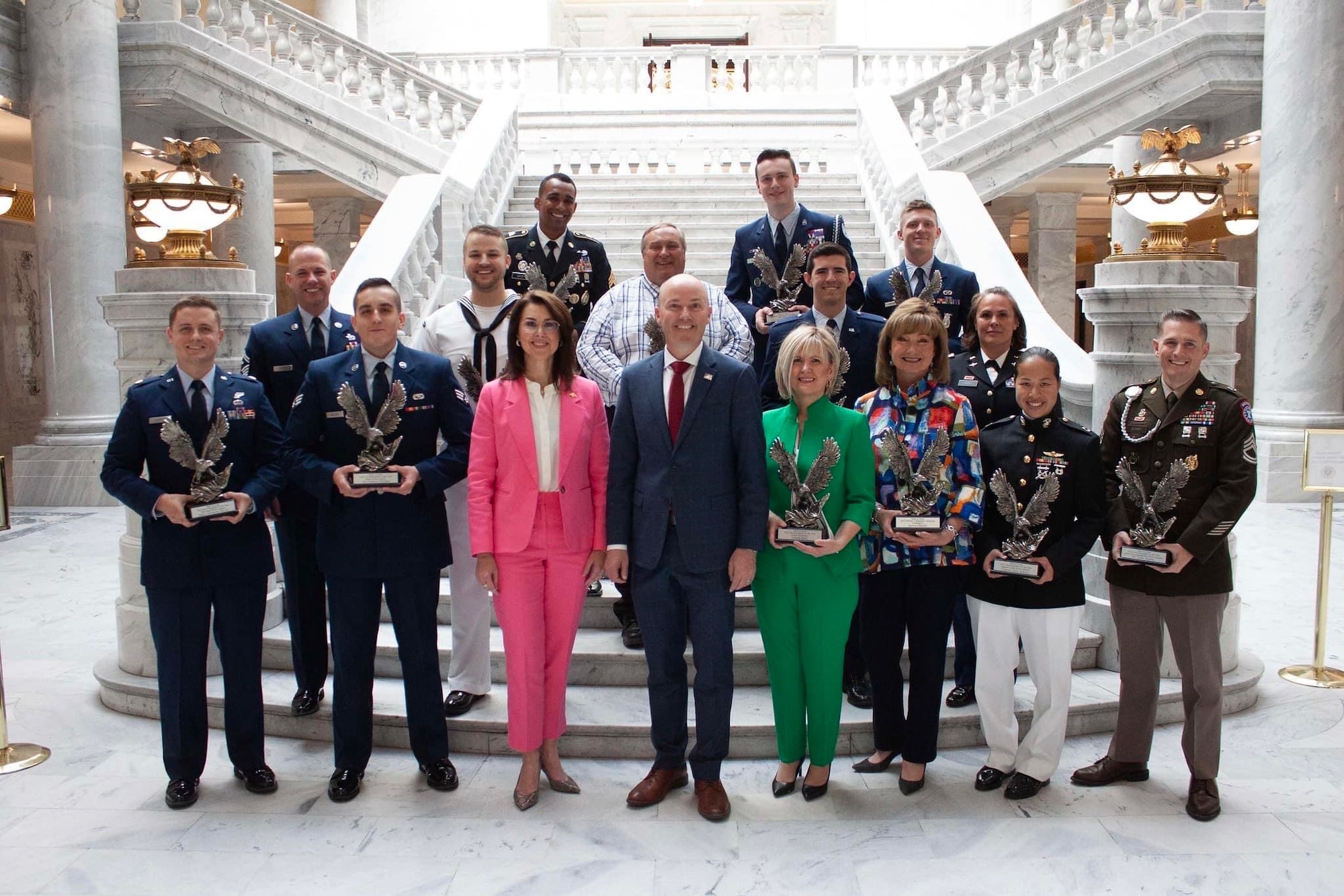 Military members and civilians stand on the steps of the Utah capitol building