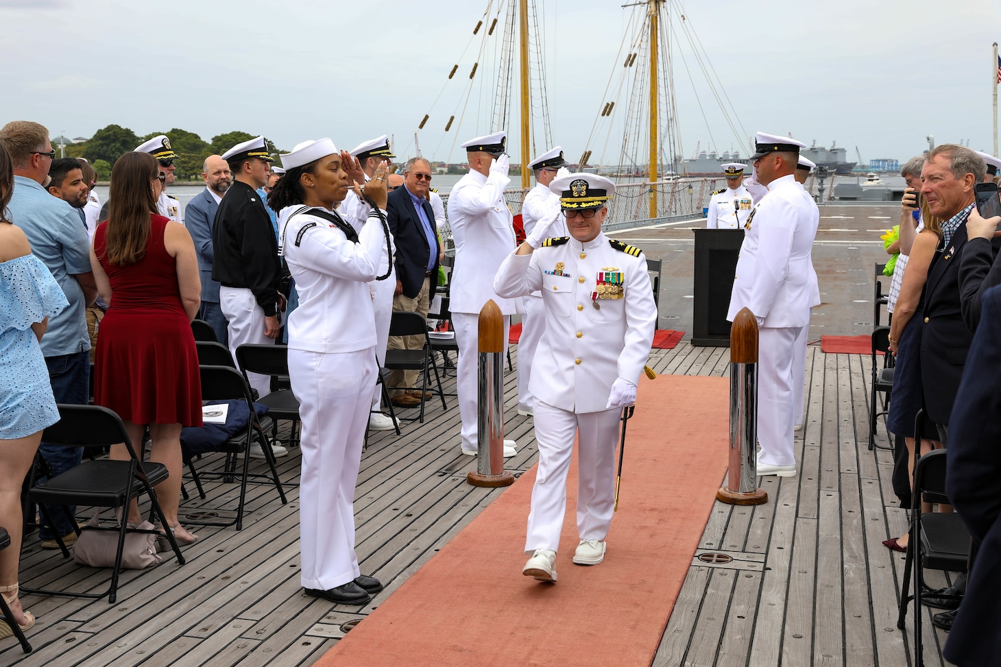 Cmdr. Ryan Heineman renders a salute to sideboys during a change of command ceremony for the Virginia-class attack submarine USS John Warner (SSN 785) aboard the decommissioned Iowa-class battleship USS Wisconsin.
