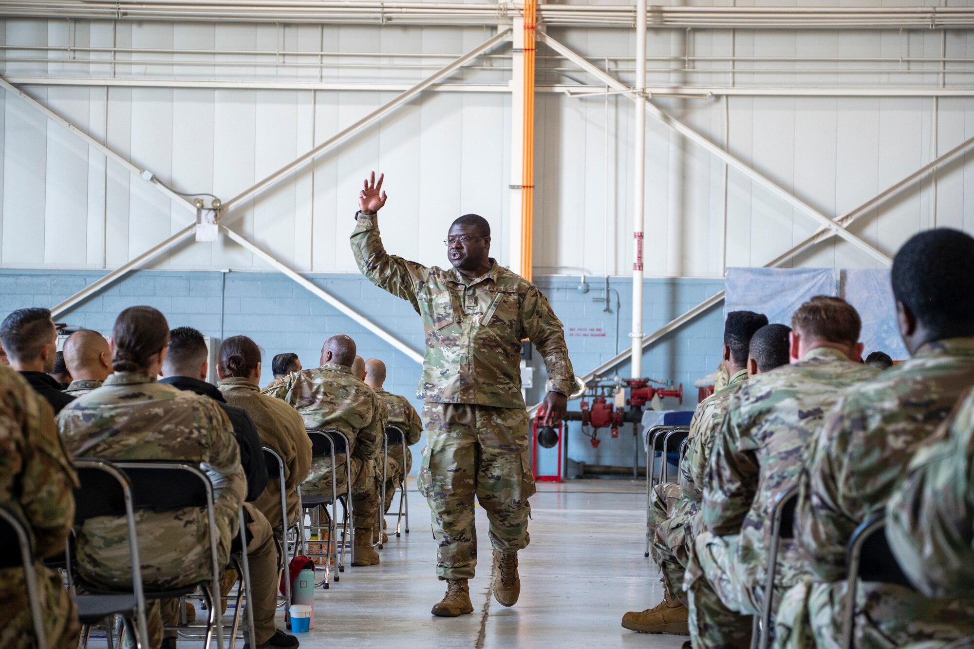 An audience in military uniform listens to a brief.