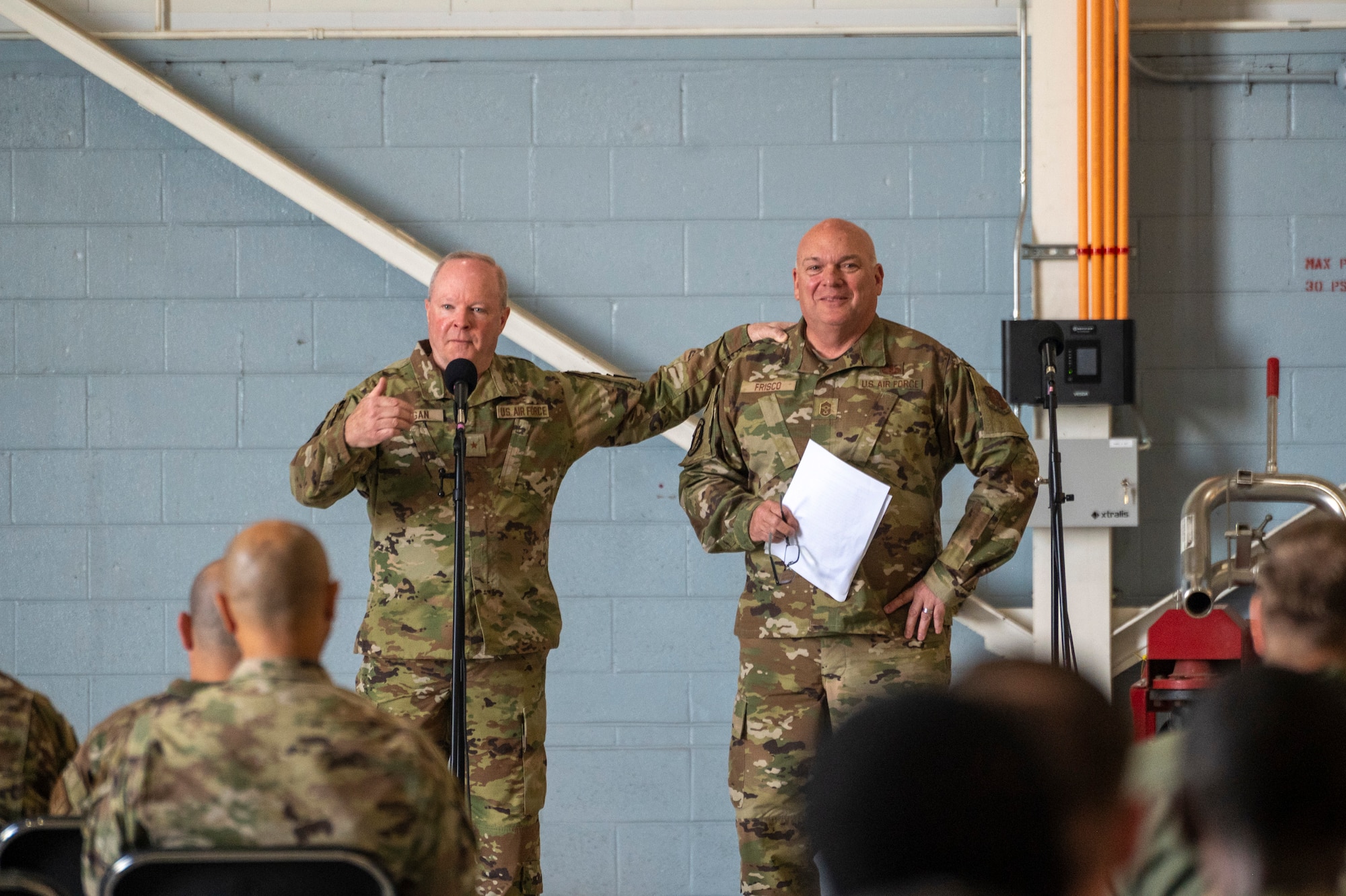 Two men brief an audience in military uniform.