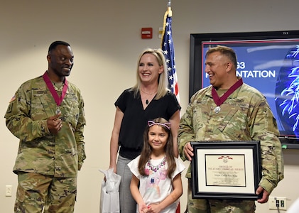 Maj. Calvin King, right, is joined by his wife, Dionna, and 6-year-old daughter, Stella, after being inducted into the Order of Military Medical Merit during a U.S. Army Medical Logistics Command awards ceremony May 16, 2023, at Fort Detrick, Maryland. Also pictured is AMLC Commander Col. Gary Cooper.