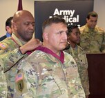 Col. Clayton Carr, left, presents Maj. Calvin King with his medallion signifying his membership in the Order of Military Medical Merit during a U.S. Army Medical Logistics Command awards ceremony May 16, 2023, at Fort Detrick, Maryland.