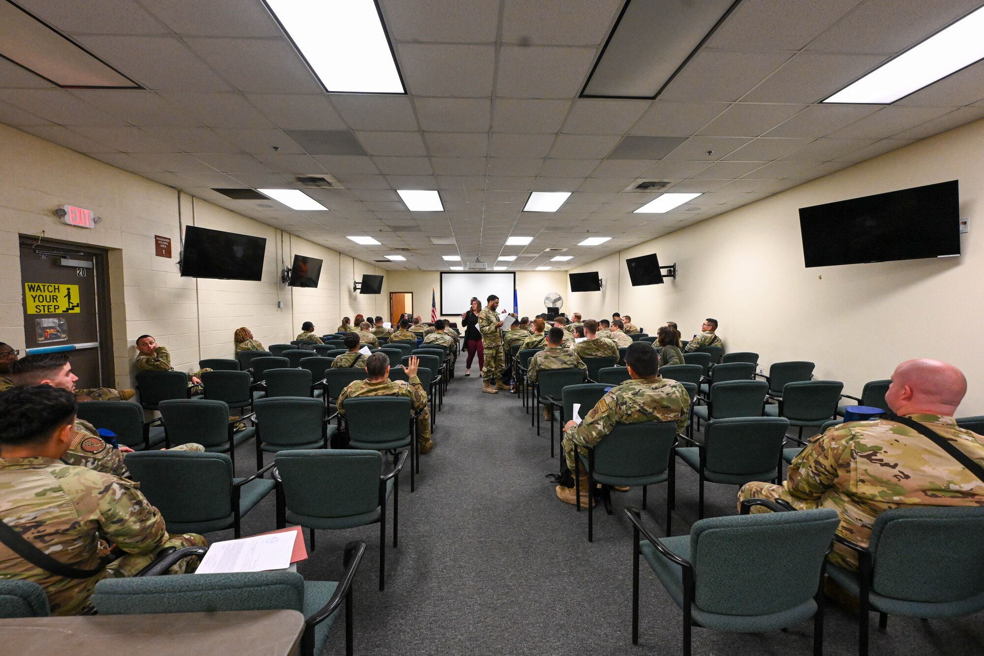 Airmen from the 97th Air Mobility Wing wait for a briefing during an exercise at Altus Air Force Base, Oklahoma, May 2, 2023. The Airmen received multiple pre-deployment briefs before going to the Chemical Biological Radiological Nuclear portion of their exercise. (U.S. Air Force photo by Senior Airman Trenton Jancze)