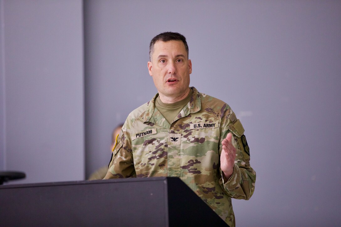 A male Soldier, Col. Bill Putnam, addresses a group while standing at a podium.